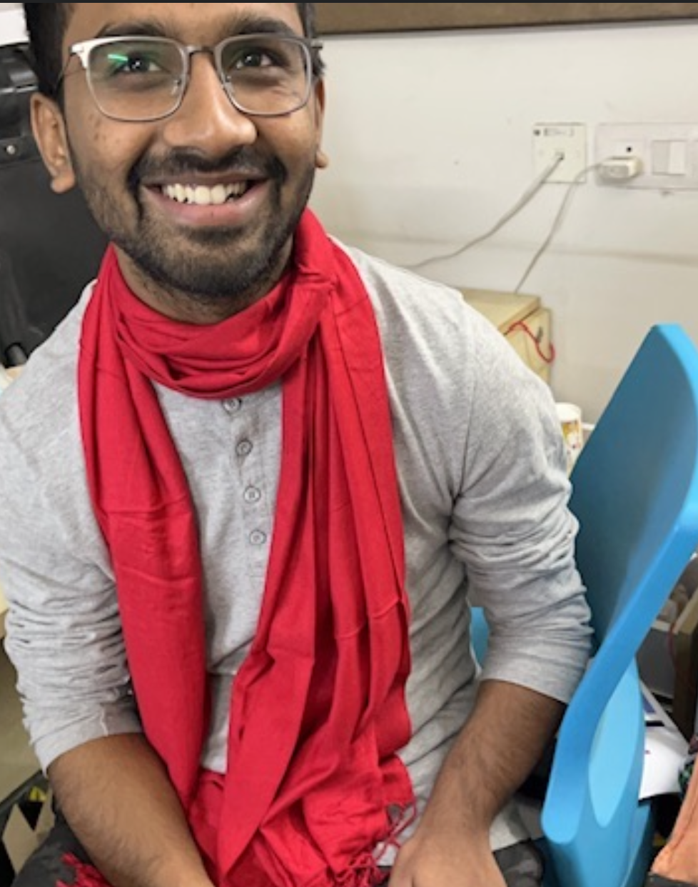 Kumar smiling in a red scarf